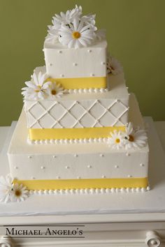 a three tiered cake with daisies on top