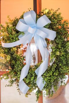 a wreath with blue ribbon hanging on the front door