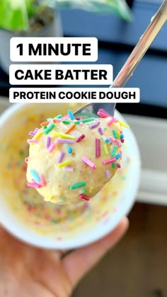 a hand holding a spoon full of cake batter and sprinkles with the text, 1 minute cake batter protein cookie dough