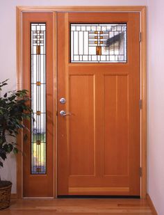 a wooden door with stained glass panels and a potted plant on the floor next to it