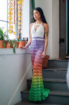 a woman is standing on the stairs wearing a colorful dress with crochet details