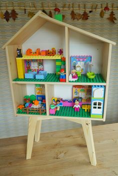 a toy house made out of legos sitting on top of a wooden table next to a wall