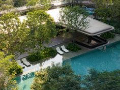 an aerial view of a swimming pool surrounded by trees and greenery with lounge chairs