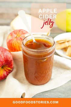 an apple cider jelly in a glass jar next to apples