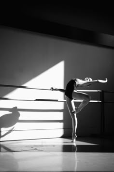 a ballerina is practicing her moves in an empty room with sunlight streaming through the window