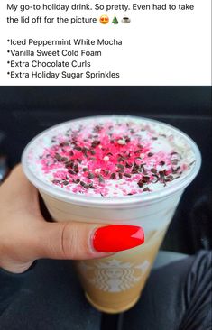 someone holding up a cup of coffee with pink and brown sprinkles on it