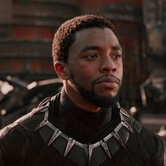 the black panther is standing in front of an iron man suit and looking at the camera