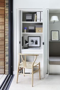 a room with a chair, desk and bookshelf next to a doorway that leads into another room