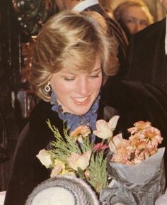 the woman is smiling and holding flowers in her hand