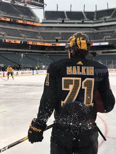 a hockey player standing on the ice in front of an empty stadium with his stick