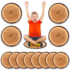 a young boy sitting on top of a pile of wood slices with his hands in the air