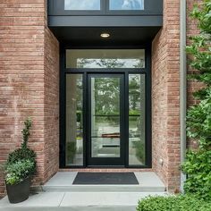 an entry way to a brick building with glass doors and plants on the side walk