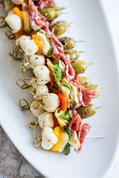 an appetizer is served on a white plate with toothpicks and vegetables