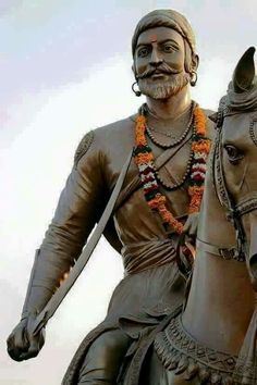 a statue of a man riding on the back of a horse with a beard and orange garland around his neck