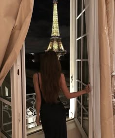 a woman looking out the window at the eiffel tower