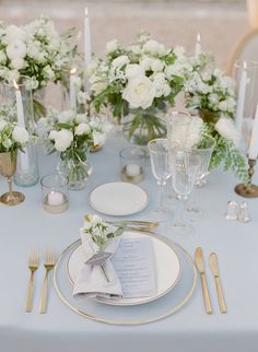 the table is set with white flowers and silverware for an elegant touch to the place setting