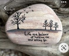 a rock with a quote on it sitting on top of a tree branch in the sand