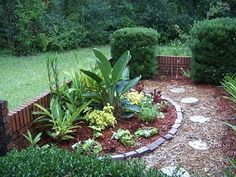 a garden with various plants and rocks in the center, surrounded by shrubbery on either side