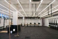 an empty gym with several rows of exercise mats and ropes hanging from the ceiling,