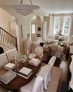 a living room filled with white furniture and lots of books on top of a wooden table