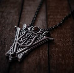 a close up of a necklace on a wooden surface with a chain hanging from it