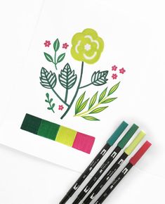 three markers and two pencils are next to some flowers