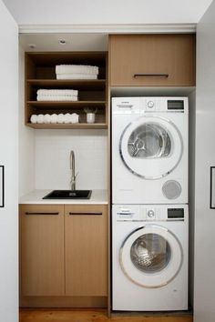 a washer and dryer in a small room with wooden cabinets on the wall