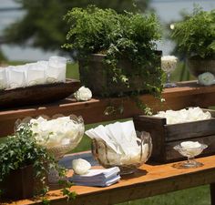 an outdoor table with flowers and other items on it, including napkins in wooden boxes