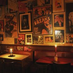 a dimly lit restaurant with posters on the wall and two tables in front of them