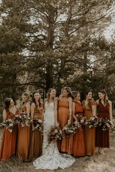 a group of women standing next to each other wearing dresses and holding bouquets in their hands