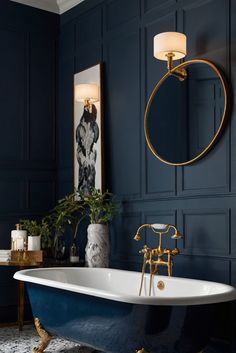 a bathroom with blue walls, gold fixtures and a claw foot tub in the middle