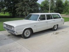 an old white station wagon parked on the side of the road