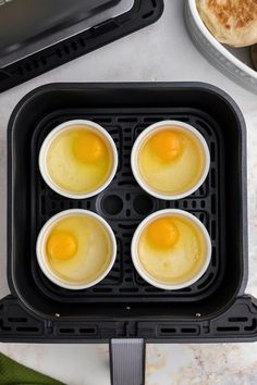 four eggs in an egg cooker on a counter top next to other food items