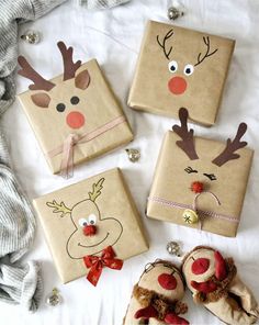 four christmas gifts wrapped in brown paper with reindeer faces and noses on them sitting on a bed