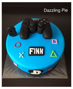 a blue cake with video game controllers on it and the words finn spelled in black