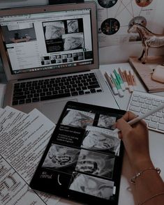 a person is working on an ipad while sitting at a desk in front of a laptop