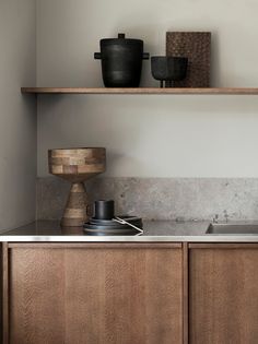 a kitchen with wooden cabinets and black pots on the shelf above the sink, along with an empty dishwasher