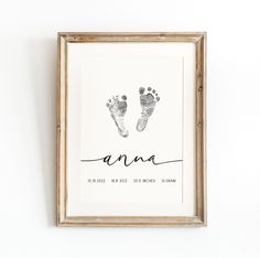 a baby's hand and foot prints are displayed in a wooden frame on the wall