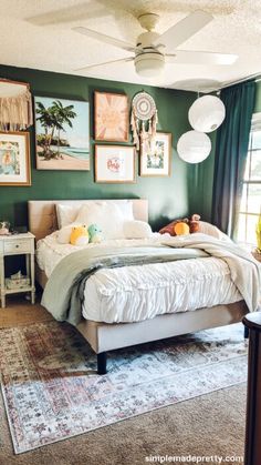 a bedroom with green walls and pictures on the wall above the bed, along with an area rug