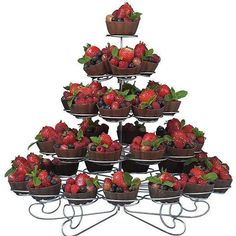 there is a large display of strawberries and other fruit in bowls on a metal stand