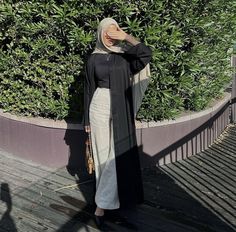 a woman standing in front of a bush wearing a black and white abak dress