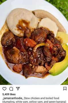 a white plate topped with meat and bananas on top of green grass next to an apple