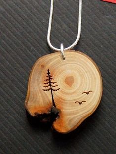 a wooden pendant with a tree on it sitting on top of a piece of wood