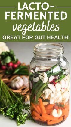 a mason jar filled with vegetables next to fresh herbs and carrots on a table