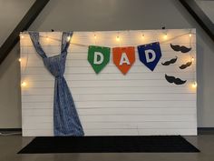 a father's day backdrop with string lights and mustaches on the wall behind it