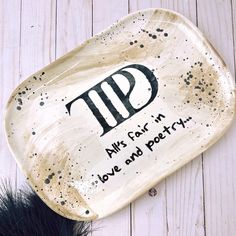 a ceramic dish with words on it sitting on a wooden table next to a feather