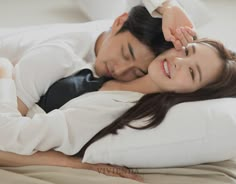 a man and woman laying in bed with their arms around each other's shoulders