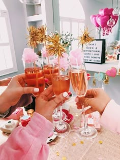 two women toasting with champagne glasses in front of pink and gold confetti