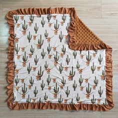 a blanket with a cactus print on it and brown ruffle trim around the edges