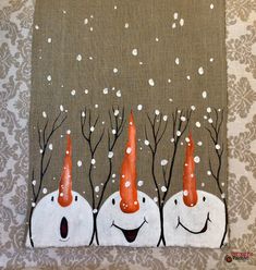 three snowmen with orange hats and trees